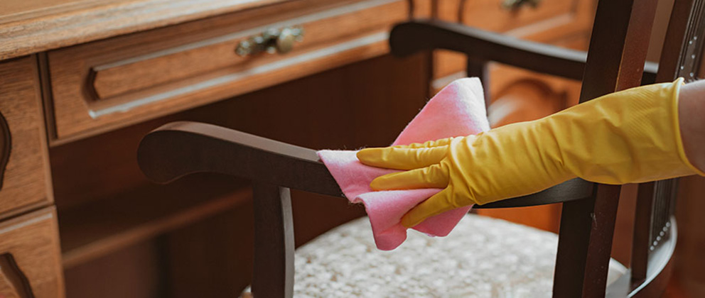 Person wiping down a wooden chair frame